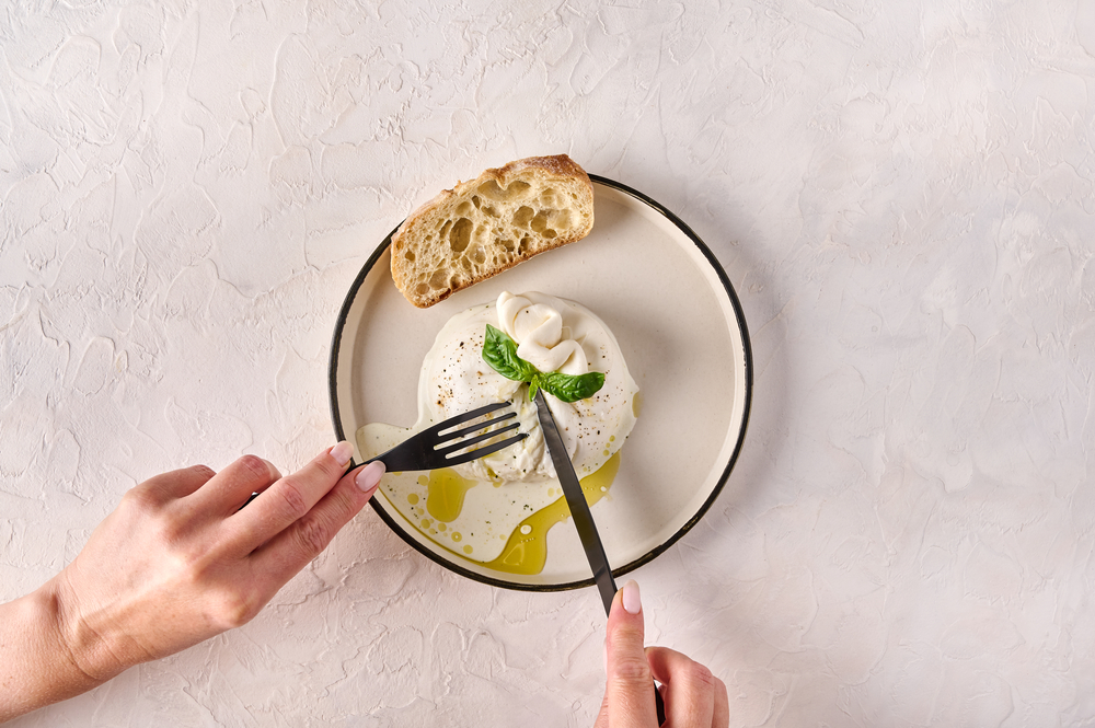 foto de pessoa cortando uma burrata de búfalo